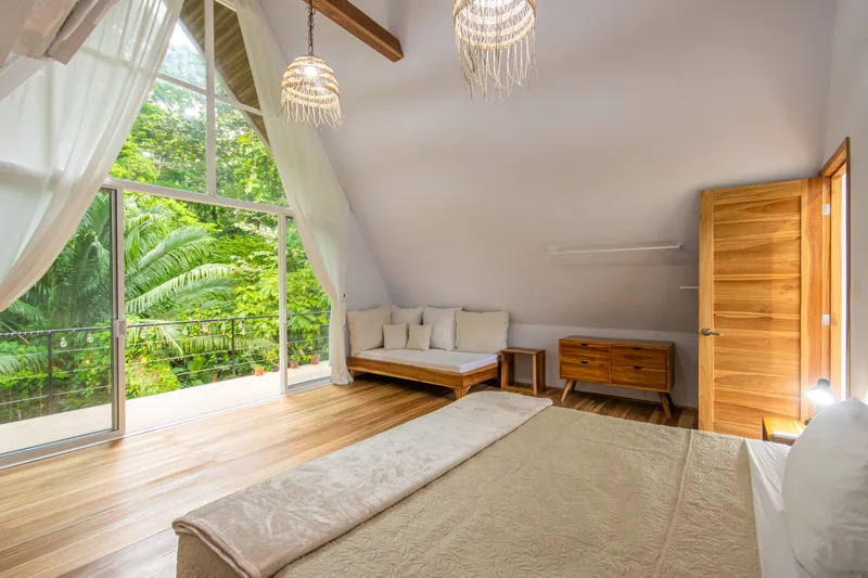 Habitación planta alta — ventanal triangular con vista a la selva